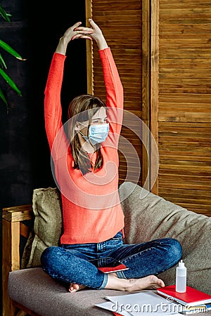 Girl in face mask at home schooling. books, laptop.online education of students and schoolchildren.on couch.Social Stock Photo