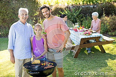 Girl, father and grandfather preparing barbecue in the park Stock Photo