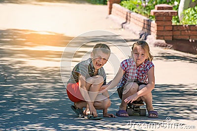 The girl feels sorry for the boy, her brother, who was injured while riding a skateboard on a road in the street Stock Photo