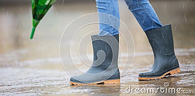 Girl feet in rubber boots with umbrella under rain in puddle Stock Photo