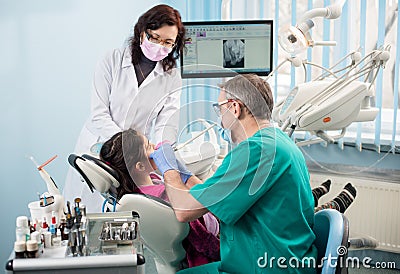 Girl with on the first dental visit. Senior pediatric dentist with nurse treating patient teeth at the dental office Stock Photo