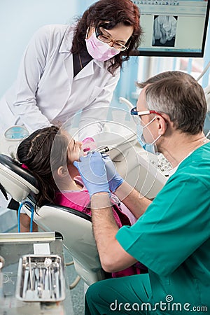 Girl with on the first dental visit. Senior pediatric dentist with nurse treating patient teeth at the dental office Stock Photo
