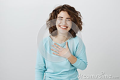 Girl is flatter to bottom of heart. Studio shot of pleased and thankful beautiful caucasian female, holding palm on Stock Photo