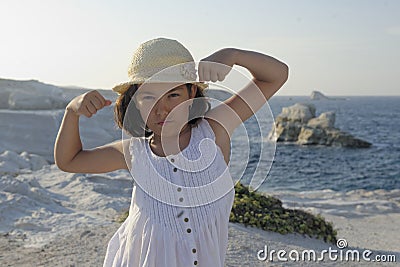 Girl flexing muscles on beach Stock Photo