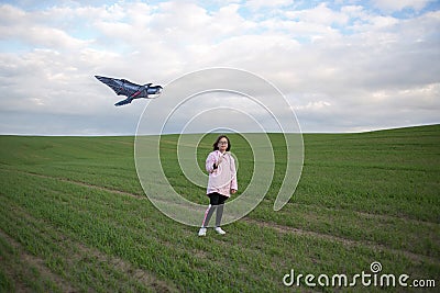 A girl flies a kite on a large green field Stock Photo
