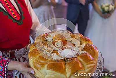 A girl in folk costume holds a cake with honey and salt in her hands. Stock Photo