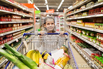 Girl with food in shopping cart at grocery store Stock Photo