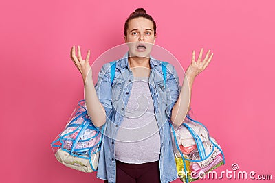 Girl freaking out, starting panic as realising its time to give birth, feels worried and anxious, holding two bags with stuff, Stock Photo