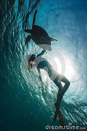 Girl freediving with cute turtle in blue sea Stock Photo