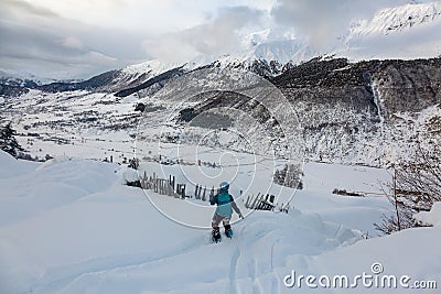 Girl freerides on a snowboard on the background of the peak of Ushba in the resort of Tetnuldi, Mestia, Svaneti, Caucasus Editorial Stock Photo