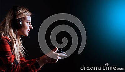 Girl gamer in headphones and with a joystick enthusiastically playing on the console Stock Photo