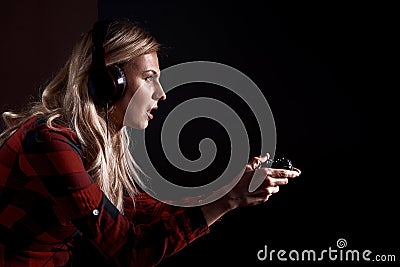 Girl gamer in headphones and with a joystick enthusiastically playing on the console Stock Photo