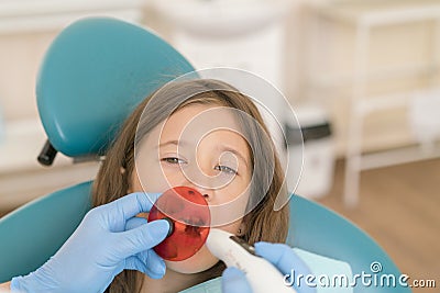 girl getting dental filling treatment at molar tooth with ultraviolet technology. Image of little girl having her teeth checked by Stock Photo