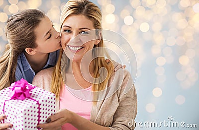 Girl giving birthday present to mother over lights Stock Photo