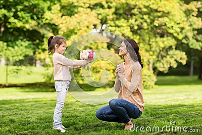 Girl giving with flowers to mother in summer park Stock Photo