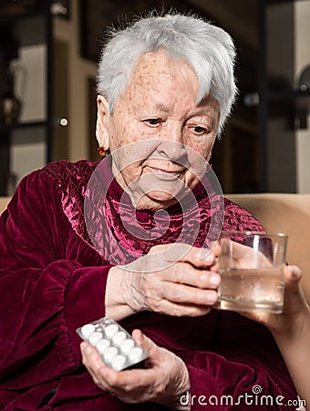 Girl giving a glass of water to the sick old woman Stock Photo