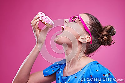 Girl is gladly going to bite a sprinkled donut with marshmallow Stock Photo