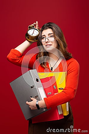 The girl in glasses carries folders, with a panic on her face on a red background. Mood stress, accounting reporting, tax audit, Stock Photo