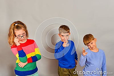 The girl with glasses and two boys point fingers forward, disposing to action. The concept of advertising and services Stock Photo