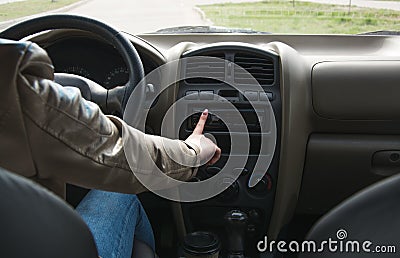 The girl goes behind the wheel of a car and switches the music in the car. Driving a car close up Stock Photo