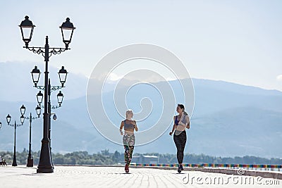 The girl goes in for sports, runs in the morning along the promenade by the sea Stock Photo