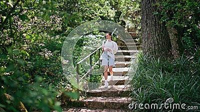 Girl going downstairs forest trail with backpack contemplating nature beauty. Stock Photo