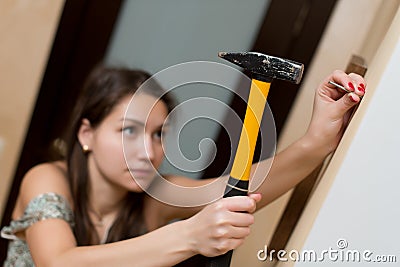 Girl is going to hammer a nail into the wall for photo frame Stock Photo