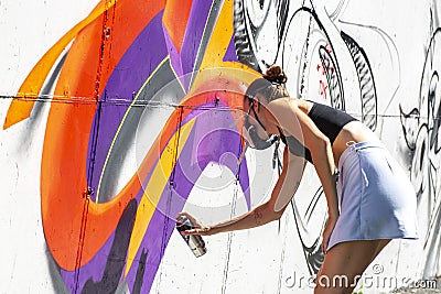 Girl graffiti artist spray painting wall art Editorial Stock Photo