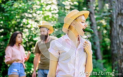 Girl with great appetite eats roasted food. Friends eating food picnic. Man feeding hungry lady with sausage on Stock Photo