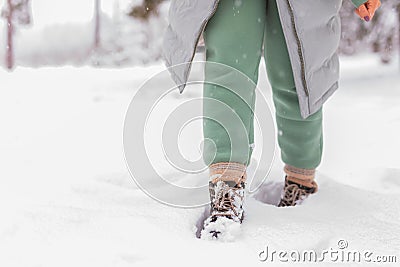 A girl in green pants walks through the snow in winter. Stock Photo