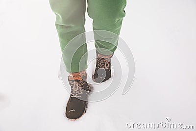 A girl in green pants walks through the snow in winter Stock Photo