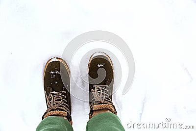 A girl in green pants walks through the snow in winter. Stock Photo