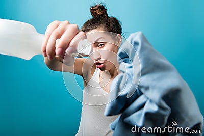 Girl grimacing and fooling around directs a sprayer and a rag into the camera Stock Photo