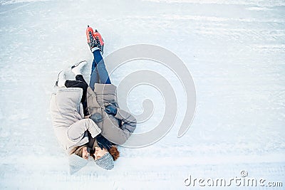 Girl and guy cuddle on snow in skates ice rink in winter, top view. Couple lover holidays Stock Photo