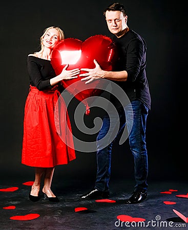 A girl and a guy hold a heart ball inflatable valentine red, board, on the floor hearts married space. inspiration Stock Photo