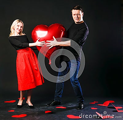 A girl and a guy hold a heart balloon inflatable, a flirting board, on the floor hearts are lovely . shape. event Stock Photo