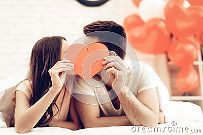 A Girl And A Guy Kiss Holding Red Heart Origami. Stock Photo