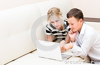 Girl and guy are sitting at a laptop Stock Photo