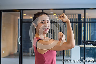 The girl in the gym stretches the muscles, shows strength, good health and smiles in the gym. Exercise healthy concepts Stock Photo