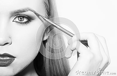 Girl half face drawing eyebrow with makeup brush Stock Photo