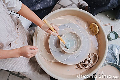 Girl hands painting clay bowl on a pottery wheel in a private workshop Stock Photo