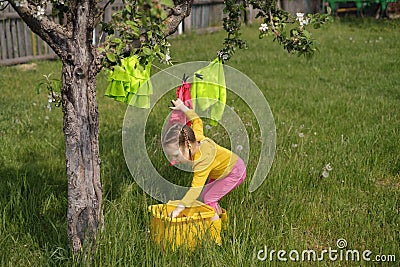 A girl hangs wet laundered clothes on a clothesline under tree in garden Stock Photo