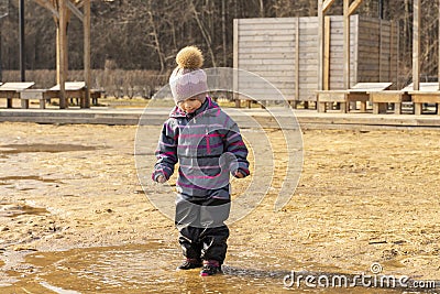 girl in a hat and overalls enters a large dirty pool Stock Photo