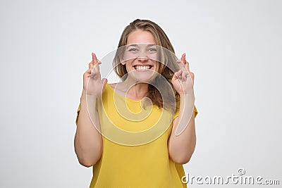 Girl having excited, superstitious and naive look, keeping fingers crossed Stock Photo