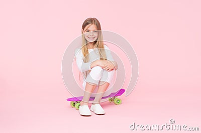 Girl having fun with penny board pink background. Kid adorable child long hair adore ride penny board. Ride penny board Stock Photo