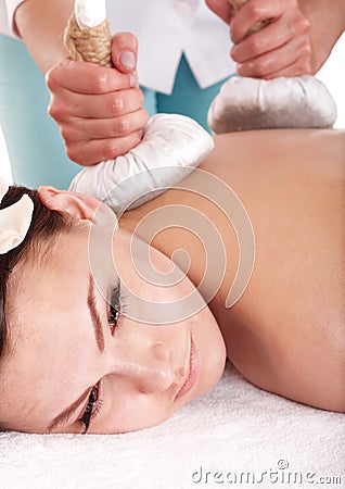 Girl having Thai herb compress massage. Stock Photo