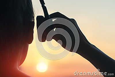 Girl in headphones listening to music in the city at sunset Stock Photo