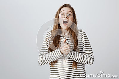 Girl is on heaven from happiness. Studio shot of pleased creative european girl clenching hands over chest and gasping Stock Photo