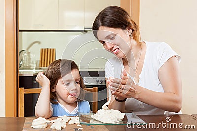 A girl with her mother learns to mold dough figurines in home Stock Photo