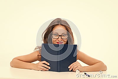 girl hiding behind book looking at camera. flirt and desire. girl read book in glasses. Introverted or extrovert girl Stock Photo